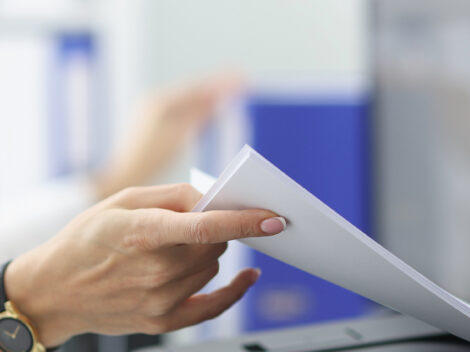 Young woman pulling paper out of printer closeup